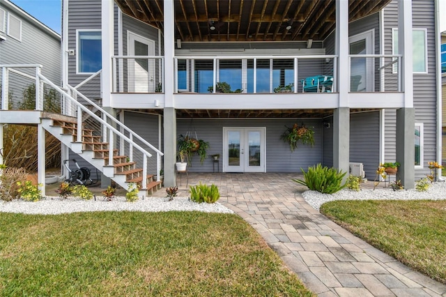 rear view of house featuring a lawn, french doors, and a patio