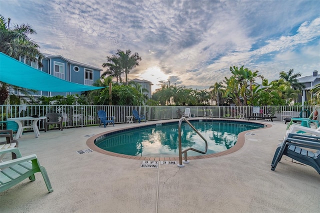 pool at dusk featuring a patio area