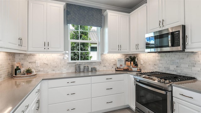 kitchen with backsplash, white cabinets, ornamental molding, and appliances with stainless steel finishes