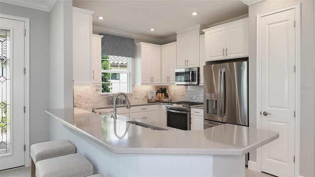 kitchen featuring kitchen peninsula, appliances with stainless steel finishes, a kitchen breakfast bar, ornamental molding, and white cabinets