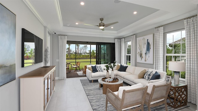 living room featuring ceiling fan, light tile patterned flooring, a raised ceiling, and ornamental molding