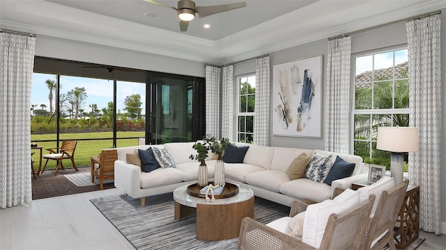 living room with light tile patterned floors, a raised ceiling, ceiling fan, and ornamental molding