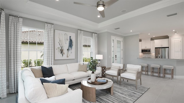 living room with a tray ceiling, a wealth of natural light, crown molding, and ceiling fan