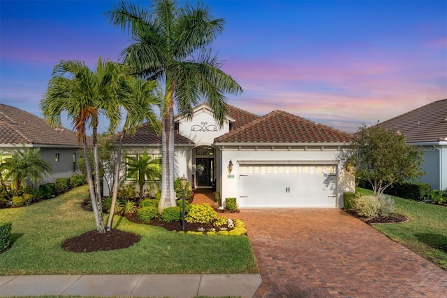 mediterranean / spanish-style house with a lawn and a garage