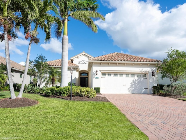 mediterranean / spanish house with a garage and a front lawn