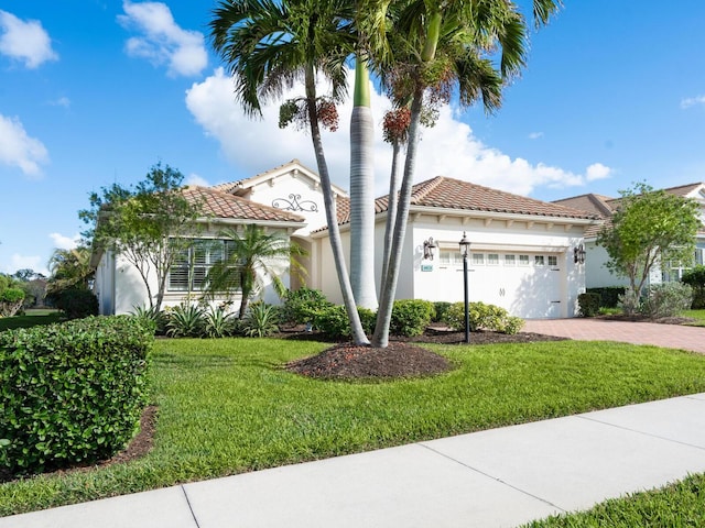 mediterranean / spanish-style house featuring a garage and a front lawn