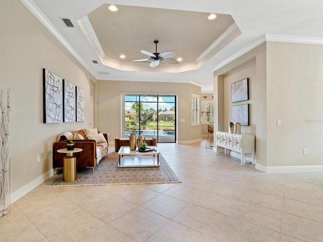 tiled living room featuring a tray ceiling, ceiling fan, and crown molding