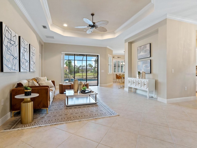 living room with light tile patterned floors, a raised ceiling, ceiling fan, and ornamental molding