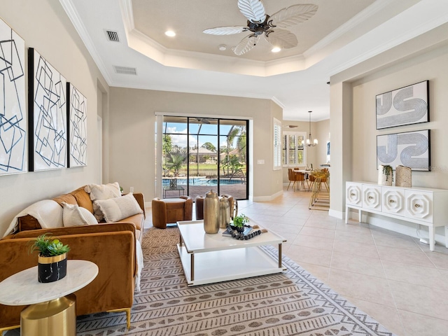 tiled living room featuring ceiling fan with notable chandelier, a tray ceiling, and ornamental molding