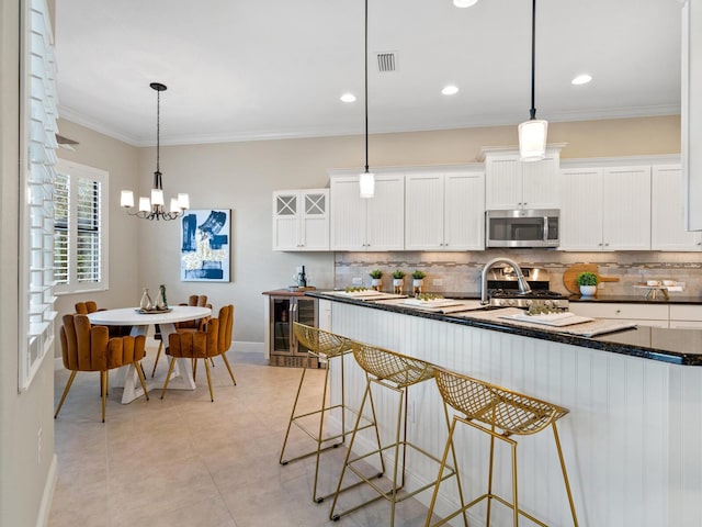 kitchen featuring pendant lighting, wine cooler, white cabinetry, and appliances with stainless steel finishes