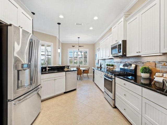 kitchen with decorative backsplash, ornamental molding, decorative light fixtures, white cabinetry, and stainless steel appliances