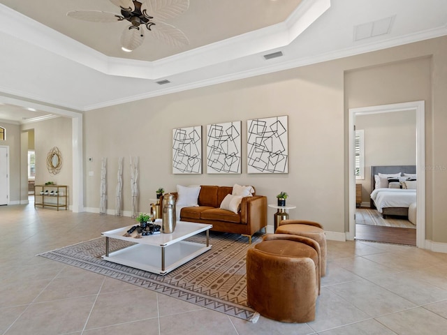 living room with ceiling fan, a raised ceiling, light tile patterned floors, and crown molding