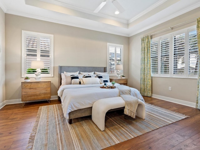 bedroom featuring hardwood / wood-style floors, ceiling fan, ornamental molding, and a tray ceiling