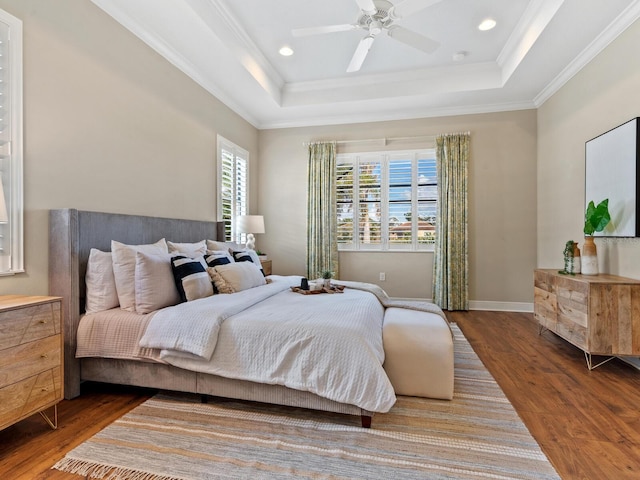 bedroom with dark hardwood / wood-style flooring, a tray ceiling, and ceiling fan