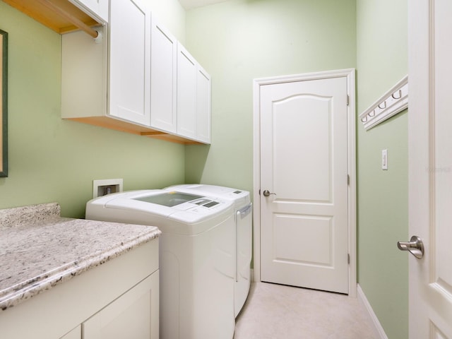 washroom with washer and clothes dryer, cabinets, and light tile patterned floors