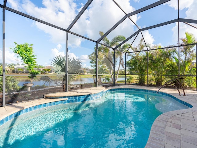 view of swimming pool with glass enclosure and a water view