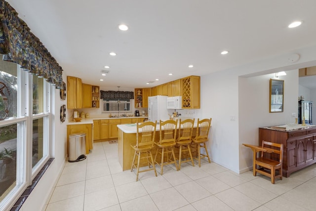 kitchen featuring light tile patterned floors, white appliances, a breakfast bar area, and sink