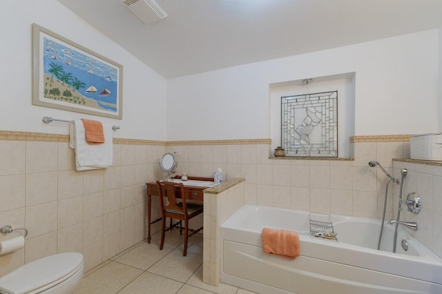 bathroom featuring tile patterned floors, a tub to relax in, toilet, and tile walls