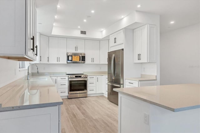 kitchen featuring white cabinets, sink, light hardwood / wood-style flooring, appliances with stainless steel finishes, and light stone counters