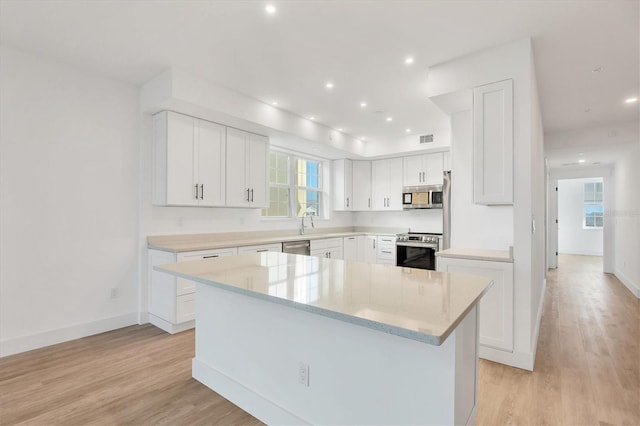 kitchen with white cabinetry, a center island, light hardwood / wood-style floors, and appliances with stainless steel finishes