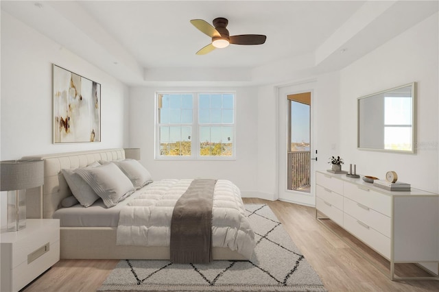 bedroom featuring ceiling fan, light wood-type flooring, multiple windows, and a tray ceiling