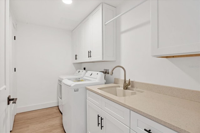 laundry room with washer and dryer, light wood-type flooring, cabinets, and sink