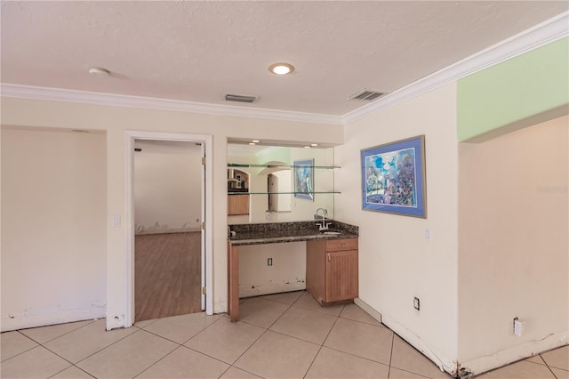 kitchen featuring a textured ceiling, sink, crown molding, and light tile patterned flooring