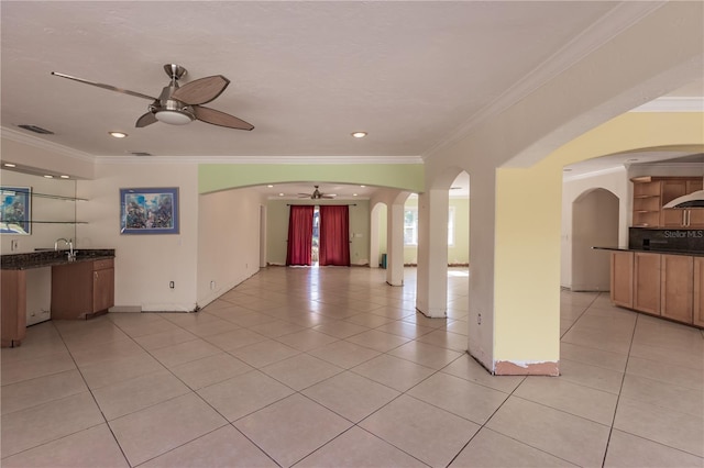 unfurnished living room with crown molding, light tile patterned floors, and ceiling fan