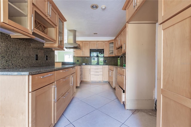 kitchen featuring wall chimney exhaust hood, tasteful backsplash, dark stone countertops, light brown cabinetry, and light tile patterned flooring