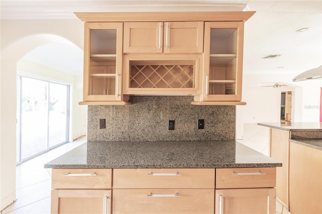 kitchen with light brown cabinetry, dark stone counters, and light tile patterned flooring