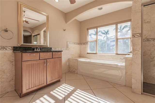 bathroom featuring a washtub, vanity, ceiling fan, tile walls, and tile patterned flooring