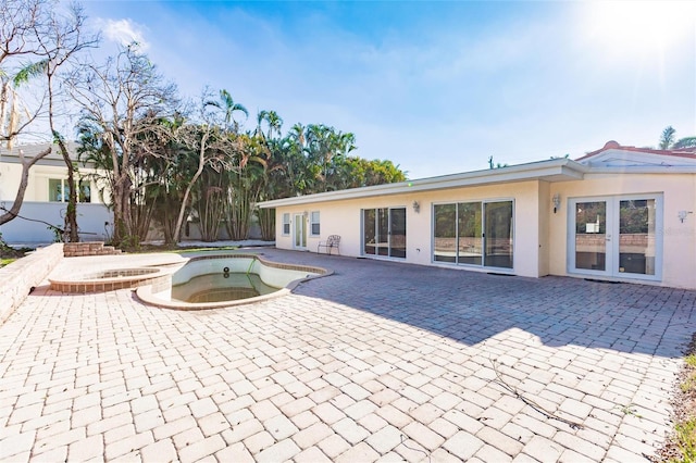 rear view of house featuring a patio area, an in ground hot tub, and french doors