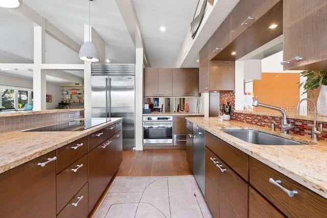 kitchen featuring pendant lighting, sink, appliances with stainless steel finishes, tasteful backsplash, and light stone countertops