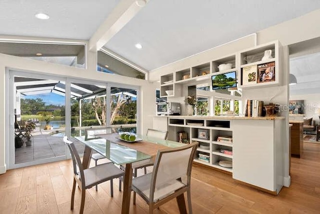 dining area featuring lofted ceiling with beams, wood-type flooring, and a healthy amount of sunlight