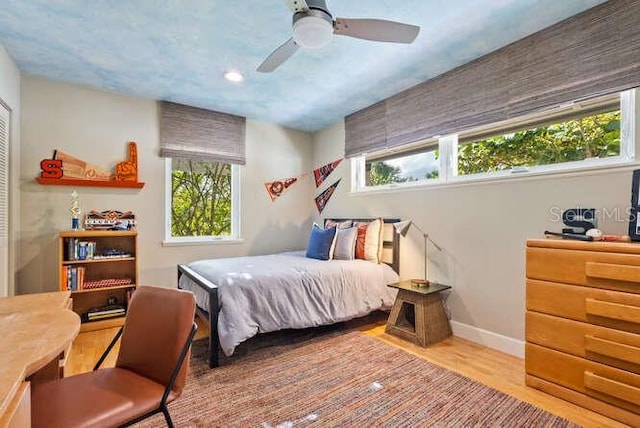 bedroom with ceiling fan, hardwood / wood-style floors, and multiple windows