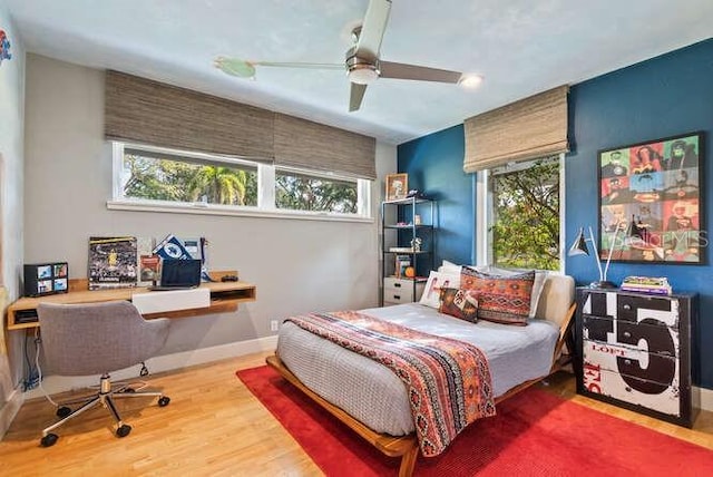 bedroom featuring hardwood / wood-style flooring, ceiling fan, and multiple windows