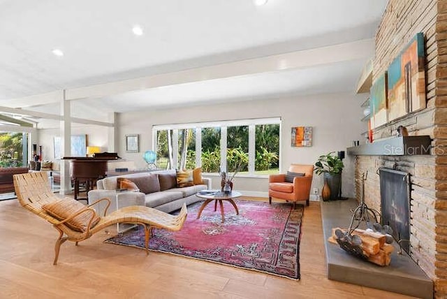 living room with a stone fireplace, light hardwood / wood-style floors, and beamed ceiling