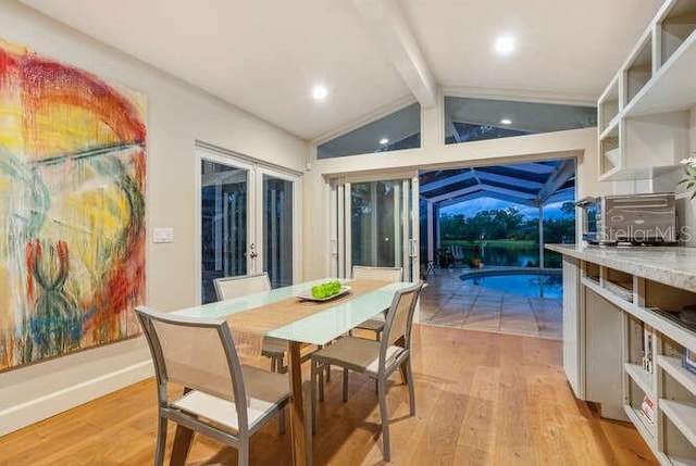 dining room featuring vaulted ceiling with beams and light hardwood / wood-style floors