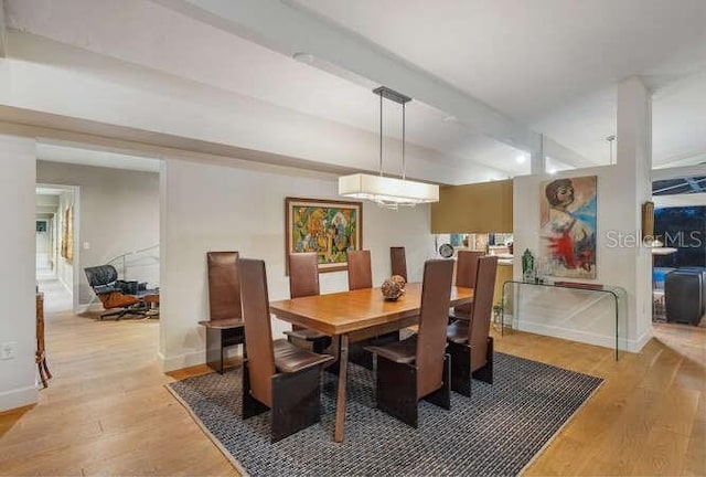 dining area with beamed ceiling and light hardwood / wood-style floors