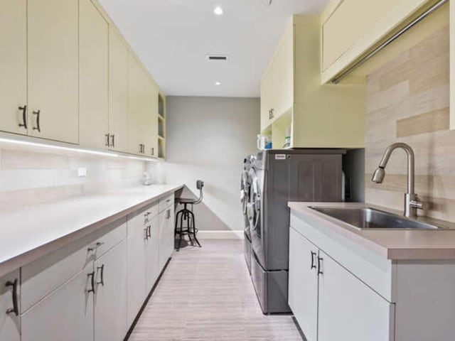 clothes washing area with cabinets, sink, and washing machine and dryer