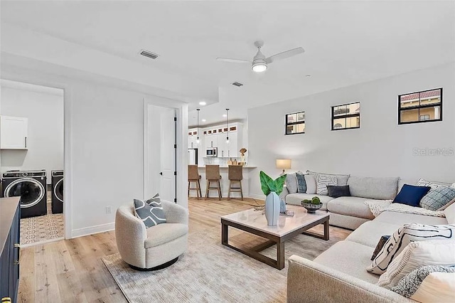 living room featuring ceiling fan, light wood-type flooring, and independent washer and dryer