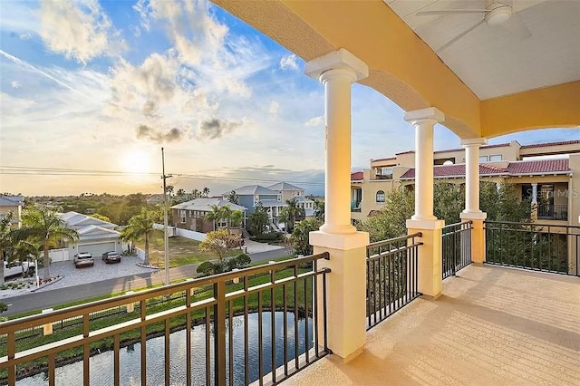 balcony at dusk featuring ceiling fan and a water view