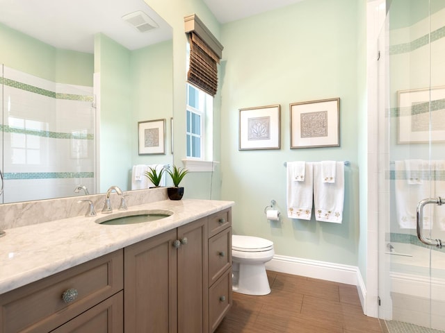 bathroom featuring vanity, toilet, and a shower with door