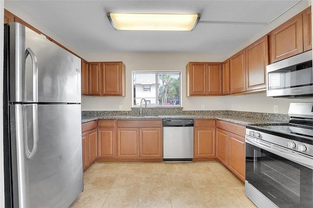 kitchen featuring stainless steel appliances, dark stone counters, and sink