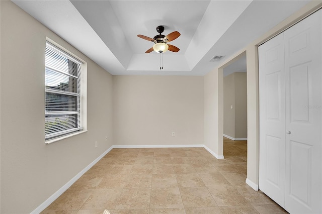 unfurnished room featuring ceiling fan and a tray ceiling