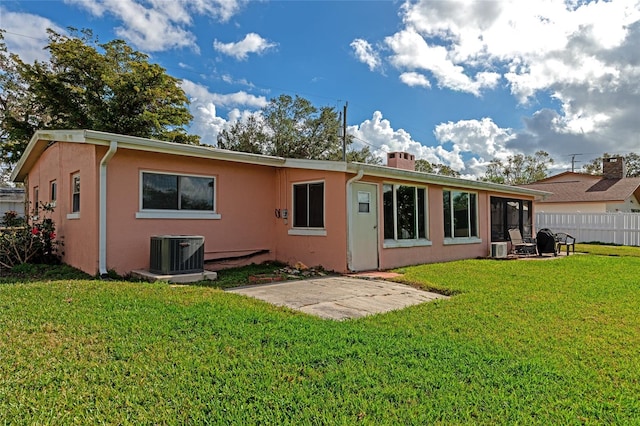 rear view of property with central AC and a yard