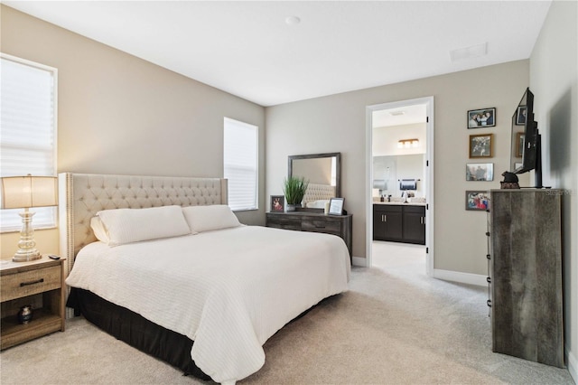 bedroom with light carpet and ensuite bath