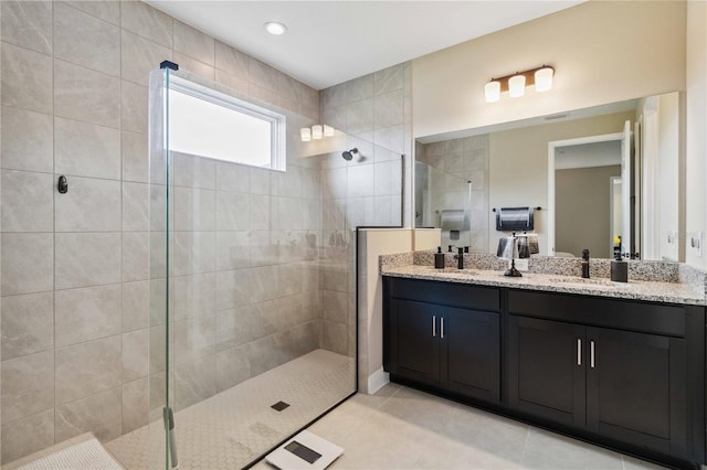 bathroom featuring tiled shower, vanity, and tile patterned flooring