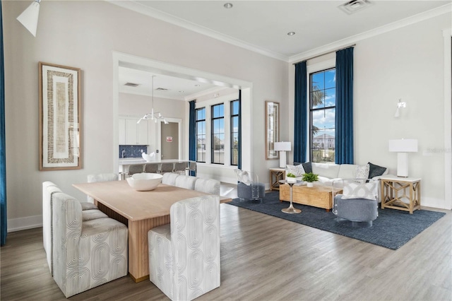 dining area with hardwood / wood-style floors, an inviting chandelier, plenty of natural light, and crown molding