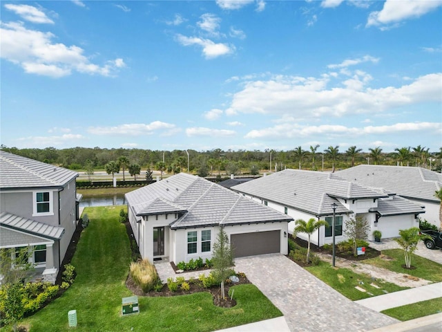 view of front of property with a garage, a water view, and a front lawn